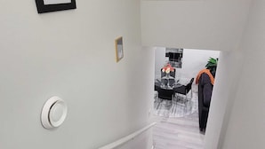 A staircase with a handrail, a framed picture on the wall, and a glimpse of a dining area in the background. - Charming 2-bedroom basement in superb Edmonton with WiFi near WEM (Edmonton)
