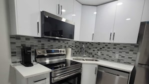 A modern kitchen with white cabinets, a black stove, a stainless steel dishwasher, and a tiled backsplash. - Charming 2-bedroom basement in superb Edmonton with WiFi near WEM (Edmonton)