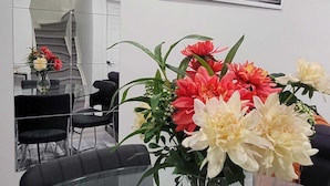 A modern dining area with a glass table, chairs, and a vase of flowers. A framed cityscape photo hangs on the wall. - Charming 2-bedroom basement in superb Edmonton with WiFi near WEM (Edmonton)