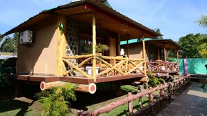 Une maison rustique en bois, dotée d’un balcon, de murs en pierre et d’un toit végétalisé.