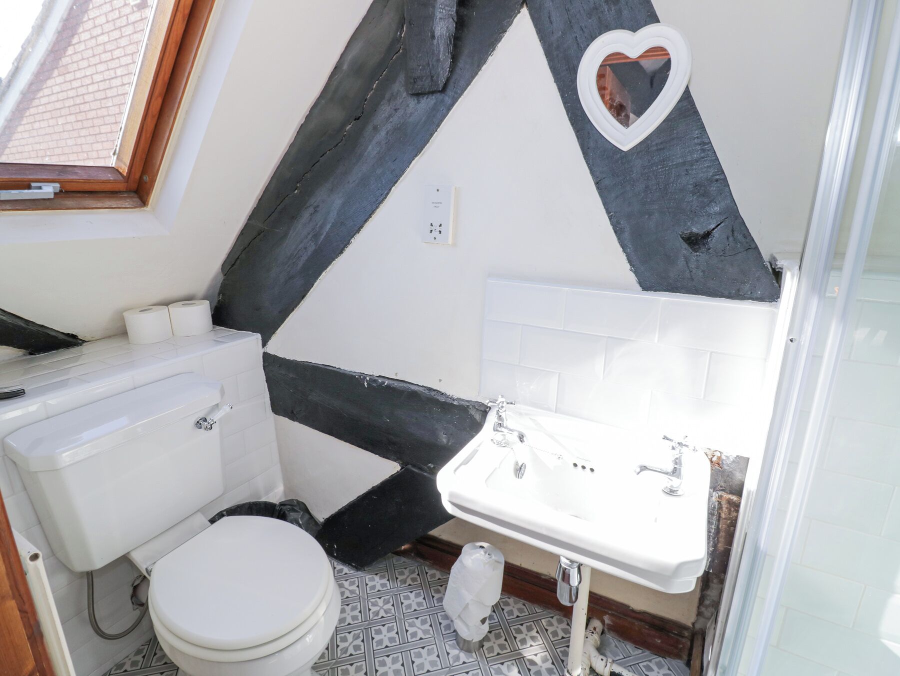 A bathroom with a white toilet, a sink, and a shower.