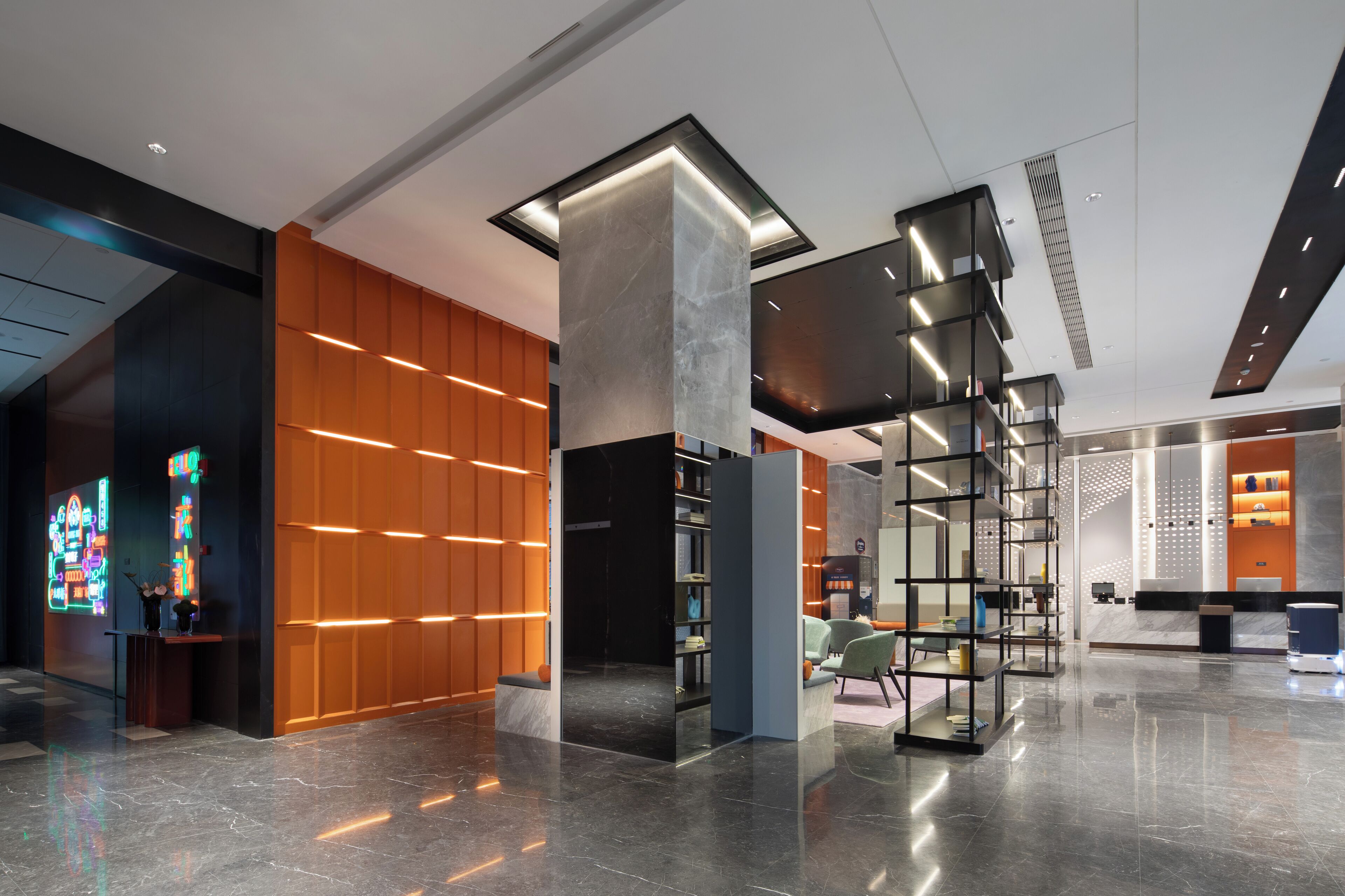 A modern lobby with a marble floor, wooden paneling, and a reception desk with a neon sign.