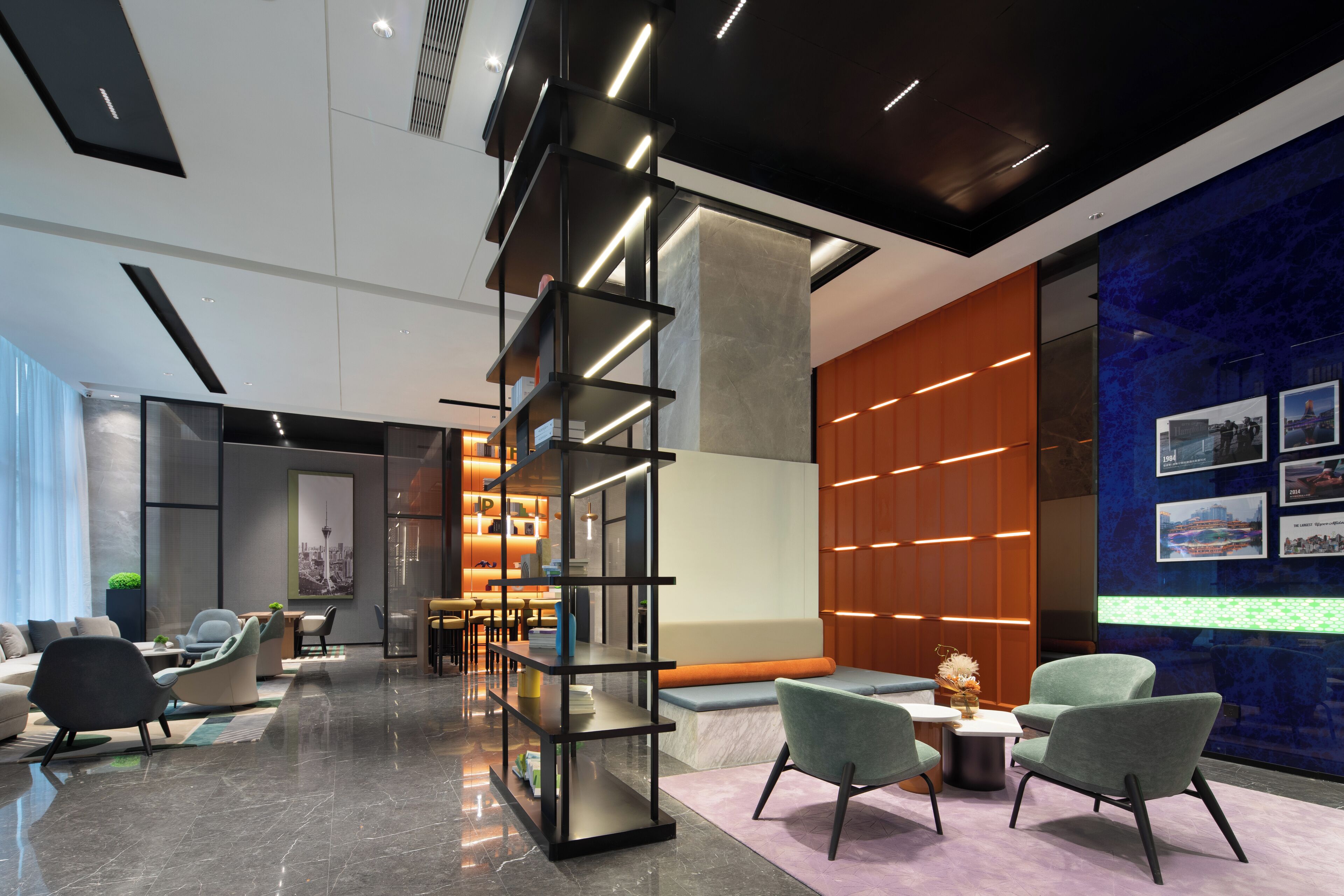 Un hall d’entrée moderne doté d’une bibliothèque centrale, d’espaces aménagés pour s’asseoir et d’un mur orné de tableaux encadrés.