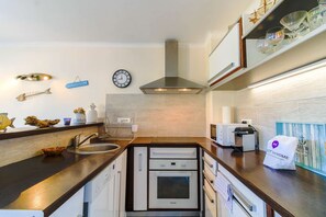 Een koelkast, een oven, een vaatwasser, kookgerei, borden en bestek