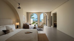A spacious bedroom with a large bed, a sitting area with a chair and a small table, and a view of the outdoors through a glass door. - Miyue Roman Holiday Bubble Pool hotel (Shenzhen)