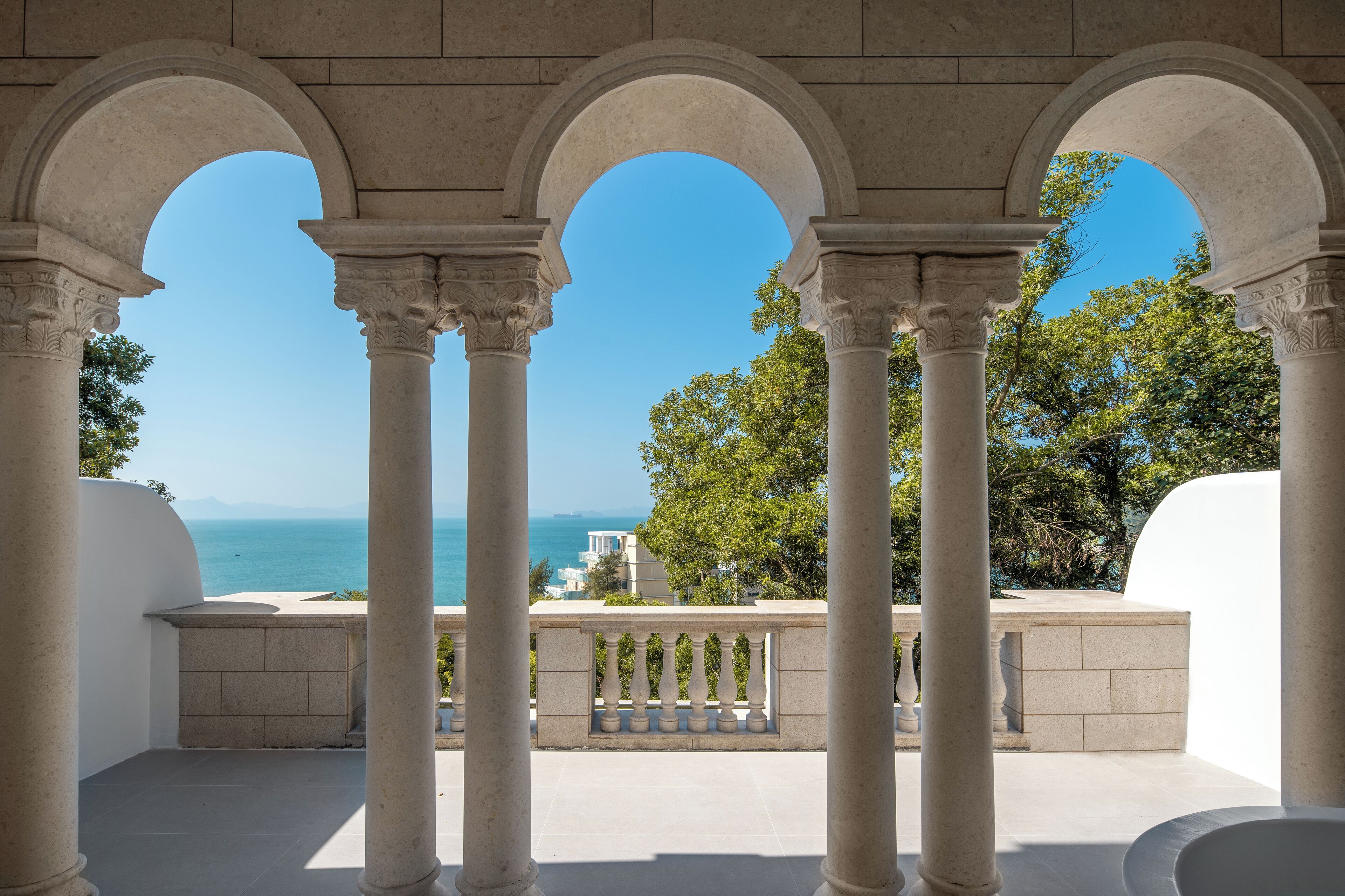 A covered outdoor area with columns and a view of the sea.