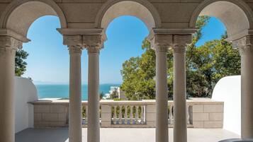 A covered outdoor area with columns and a view of the sea.
