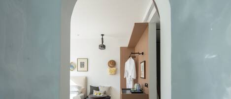 Une chambre d’hôtel moderne au design minimaliste, comprenant un lit, un petit coin salon et une kitchenette.