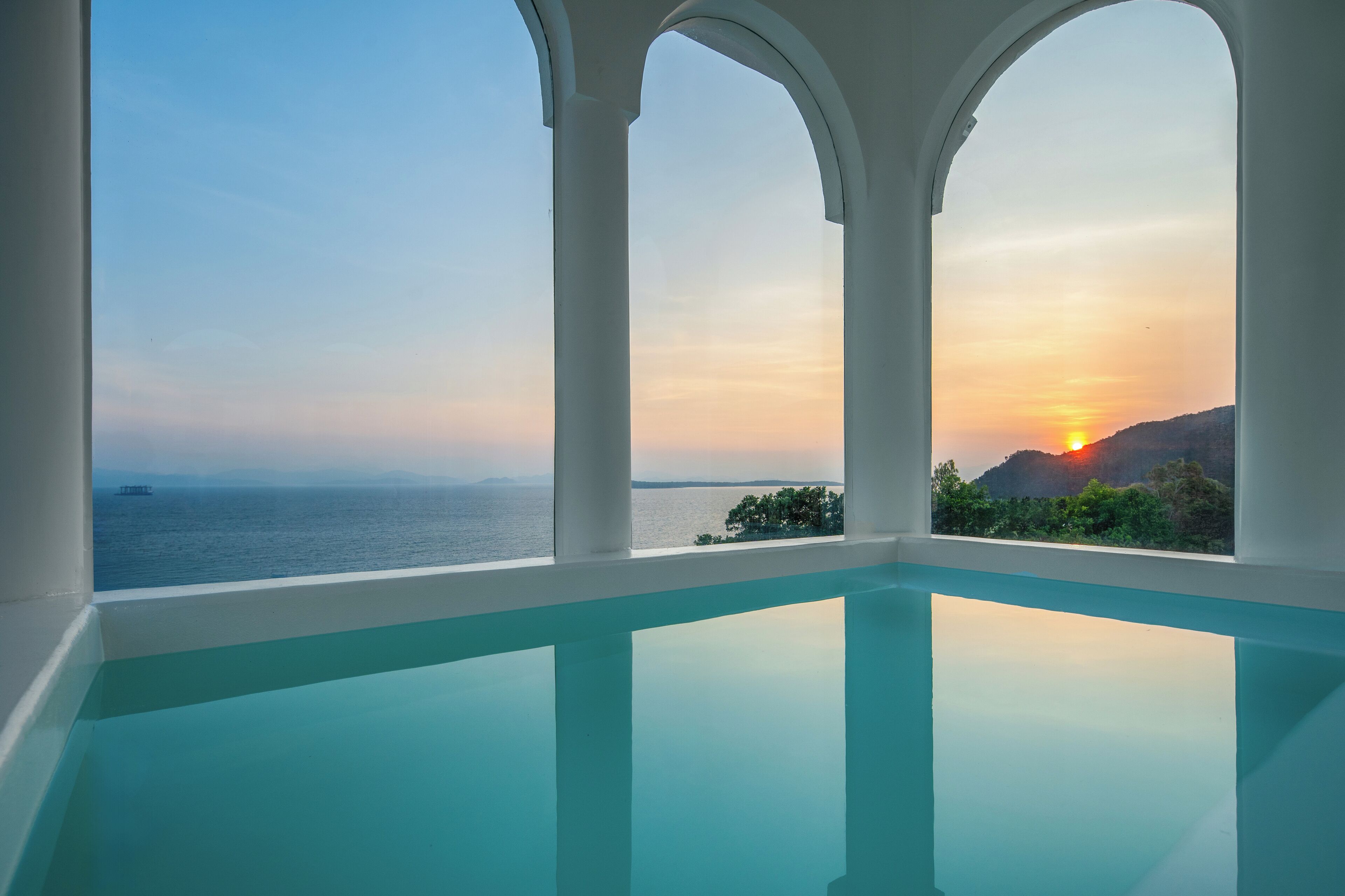 A pool with a view of the sea and a sunset.
