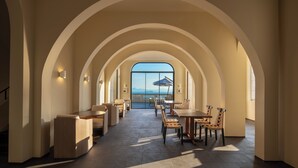 A spacious indoor area with arched ceilings, a dining area with tables and chairs, and a large window offering a view of the sea. - Miyue Roman Holiday Bubble Pool hotel (Shenzhen)