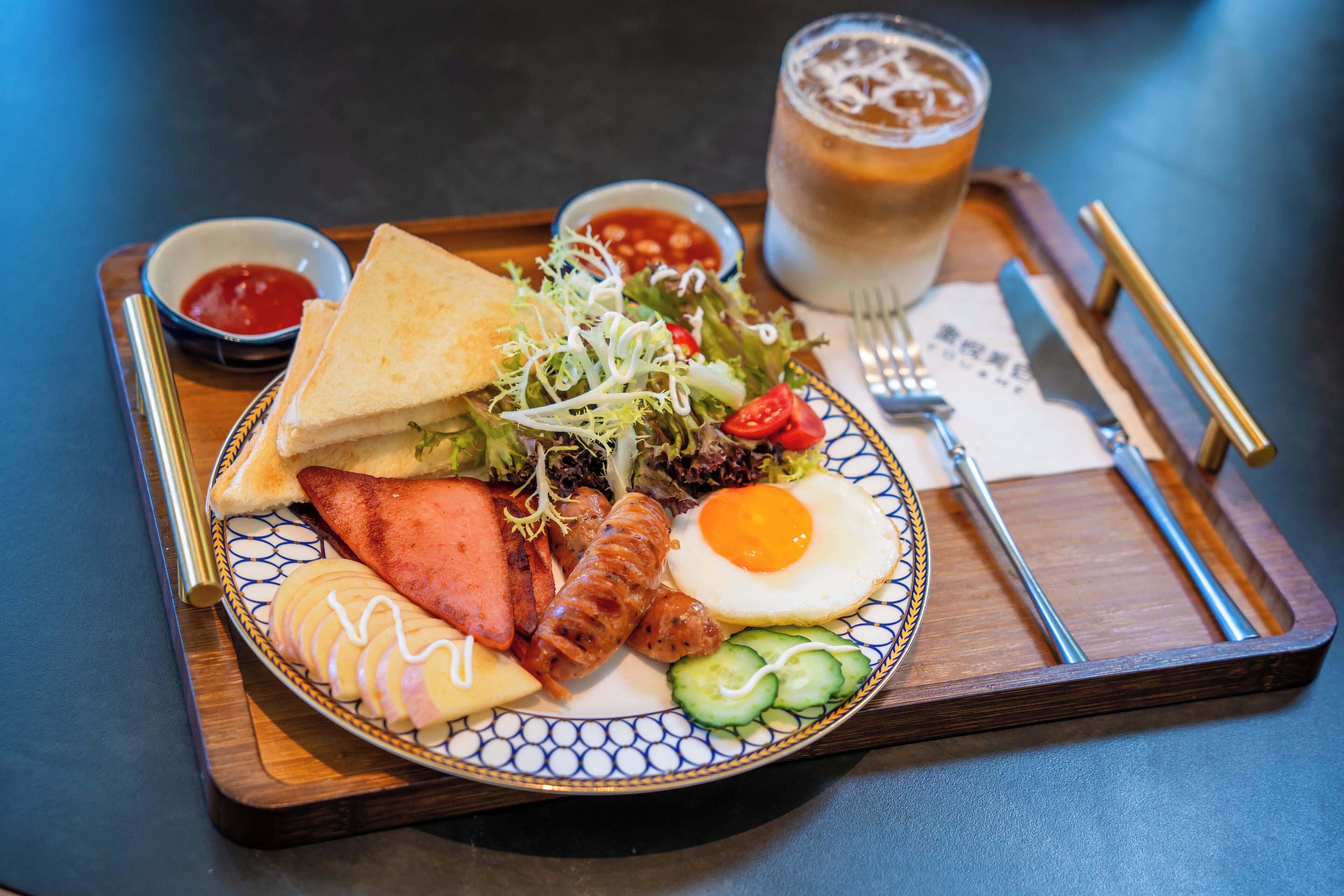 A tray with a plate of food including a sandwich, egg, vegetables, and a drink.