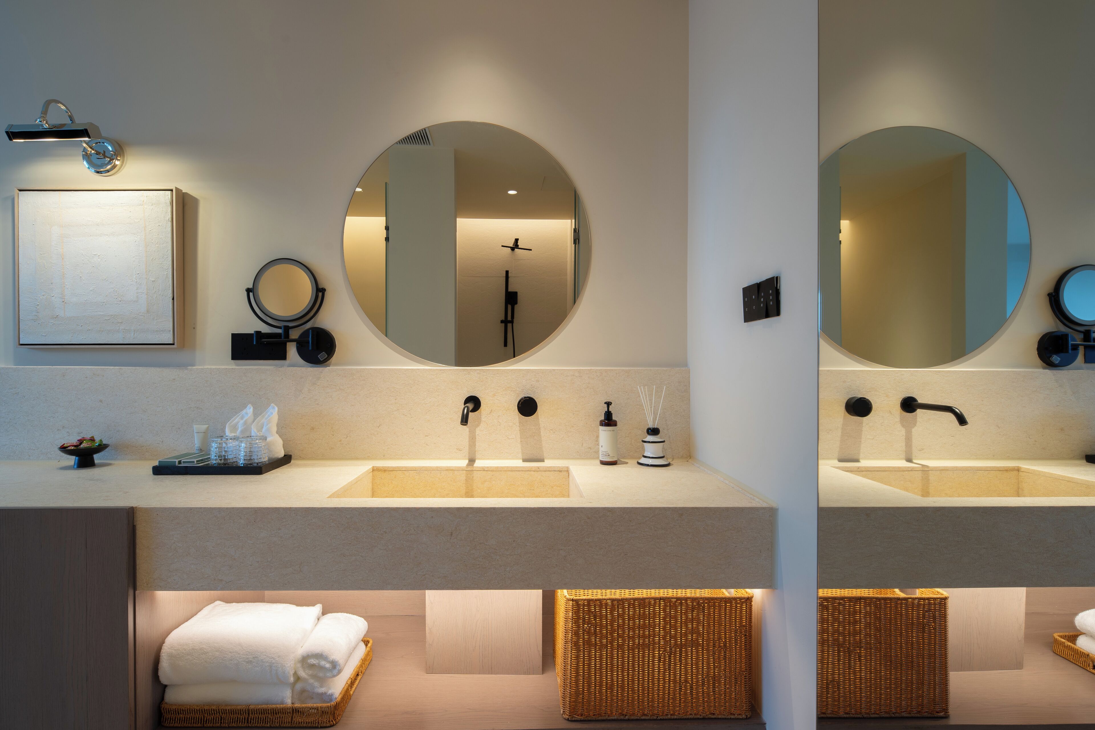 Une salle de bain moderne avec deux lavabos, un grand miroir, un porte-serviettes et un petit tableau encadré.
