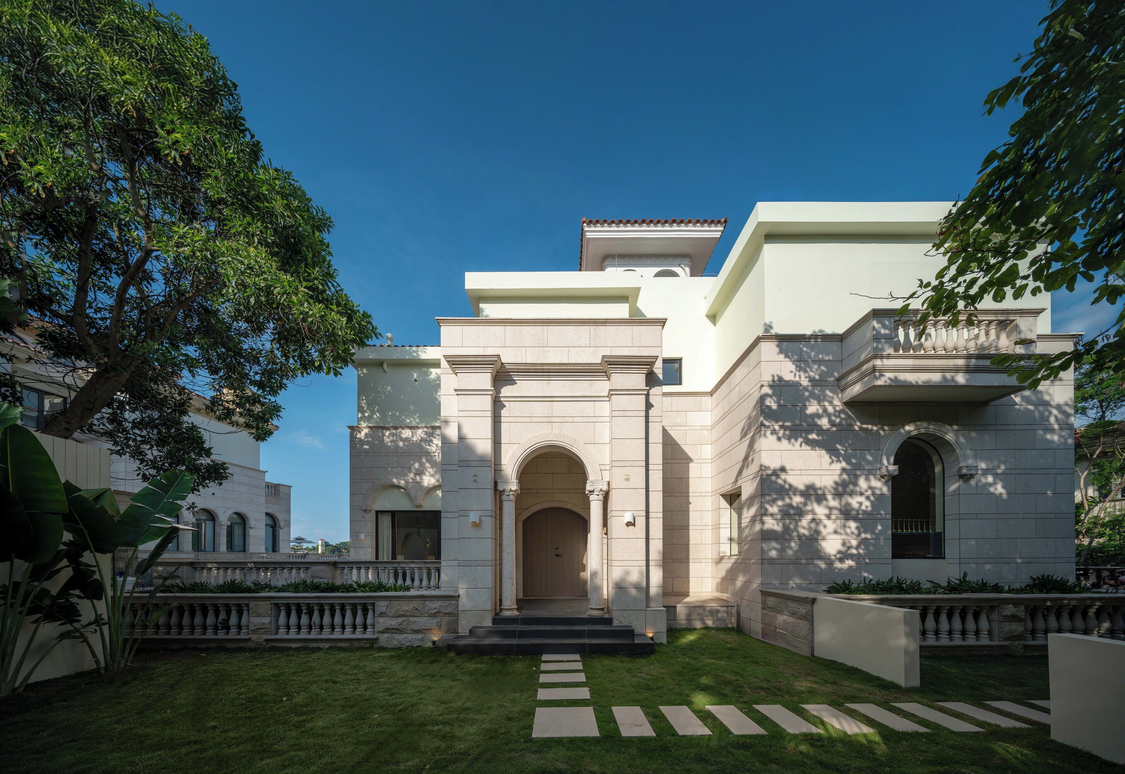 A stately building with a grand entrance, a well-manicured lawn, and classical architecture.
