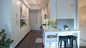 A modern kitchen with white cabinetry, a central island with stools, and a small potted plant on the counter. - Modern studio apartment with roof top, WiFi, AC in enjoyable Irvine (Irvine)