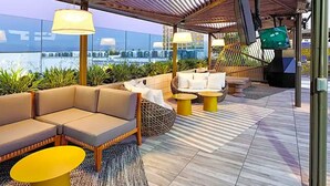 An outdoor seating area with cushioned sofas, round tables, and a view of the cityscape. - Modern studio apartment with roof top, WiFi, AC in enjoyable Irvine (Irvine)
