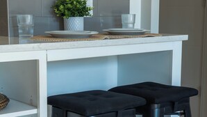 A kitchen with a white countertop, two black stools, a potted plant, and a tiled backsplash. - Modern studio apartment with roof top, WiFi, AC in enjoyable Irvine (Irvine)