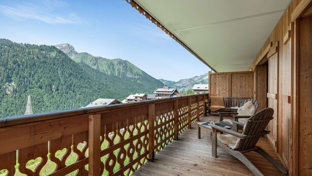 Ein Holzbalkon mit Blick auf Berge und eine Chalet.