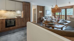 Eine moderne Küche mit Holzausstattung, einem eingebauten Backofen und einem Essbereich mit Tisch für vier Personen.