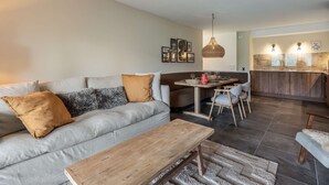 Ein modernes Wohnzimmer mit Sofa, Couchtisch und Essbereich mit Stühlen und Tisch.