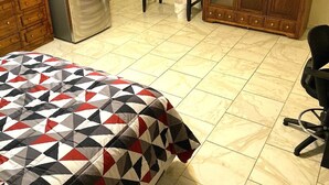 Une chambre à coucher comprenant un lit, une télévision, un réfrigérateur, une armoire en bois et un bureau avec une chaise.