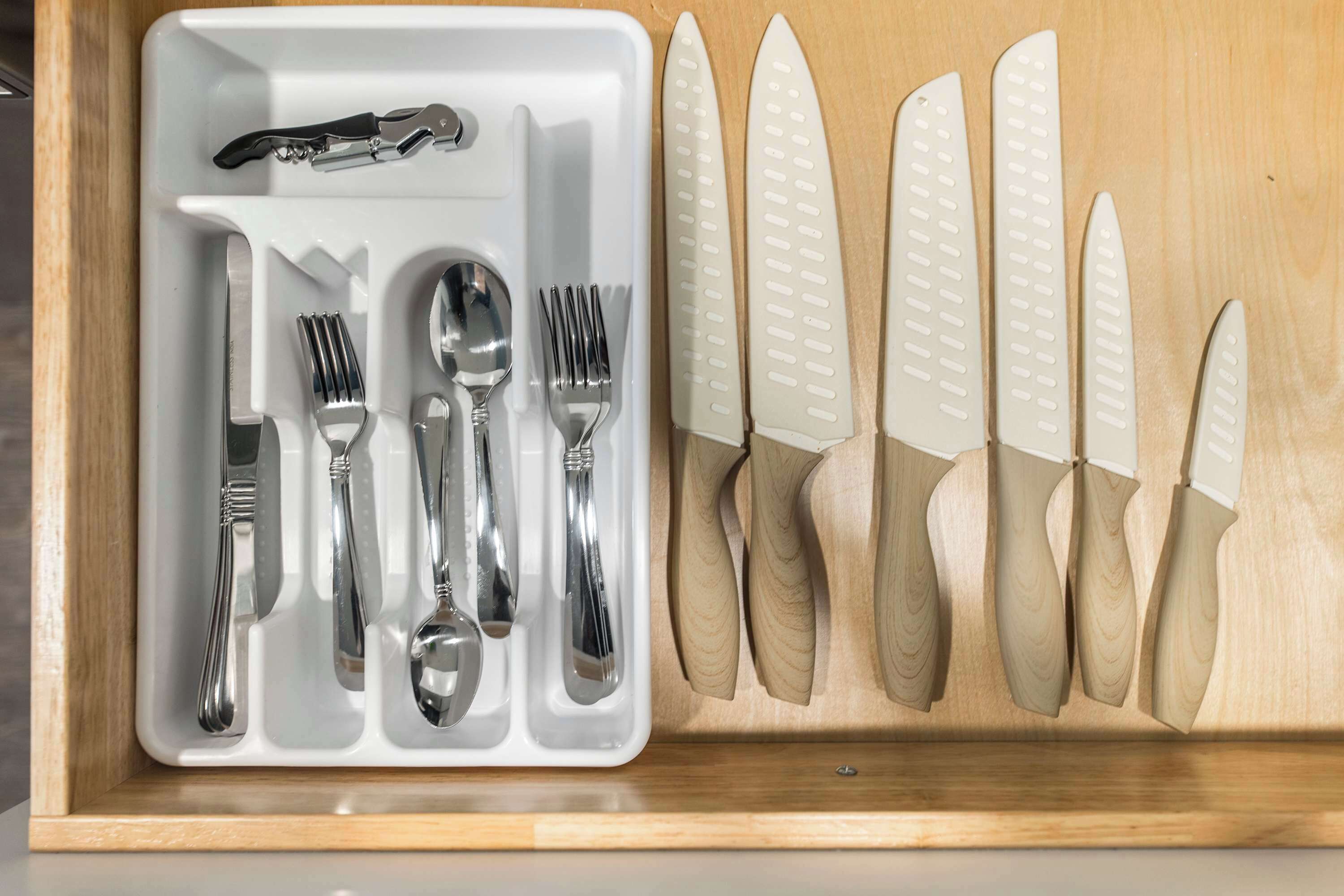 A drawer containing a set of silverware and knives.