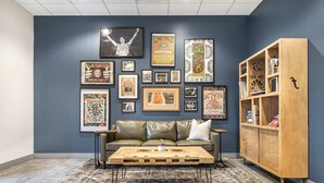 Una habitación con pared azul oscuro, sofá de cuero verde, una mesa de centro de madera y una estantería.