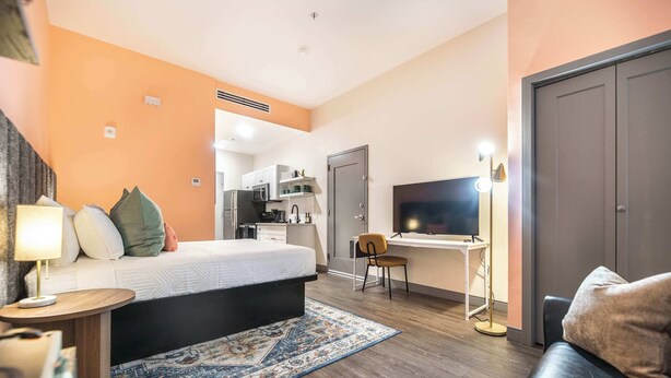 Een hotelkamer met een bed, bureau, televisie, stoel en een bank.