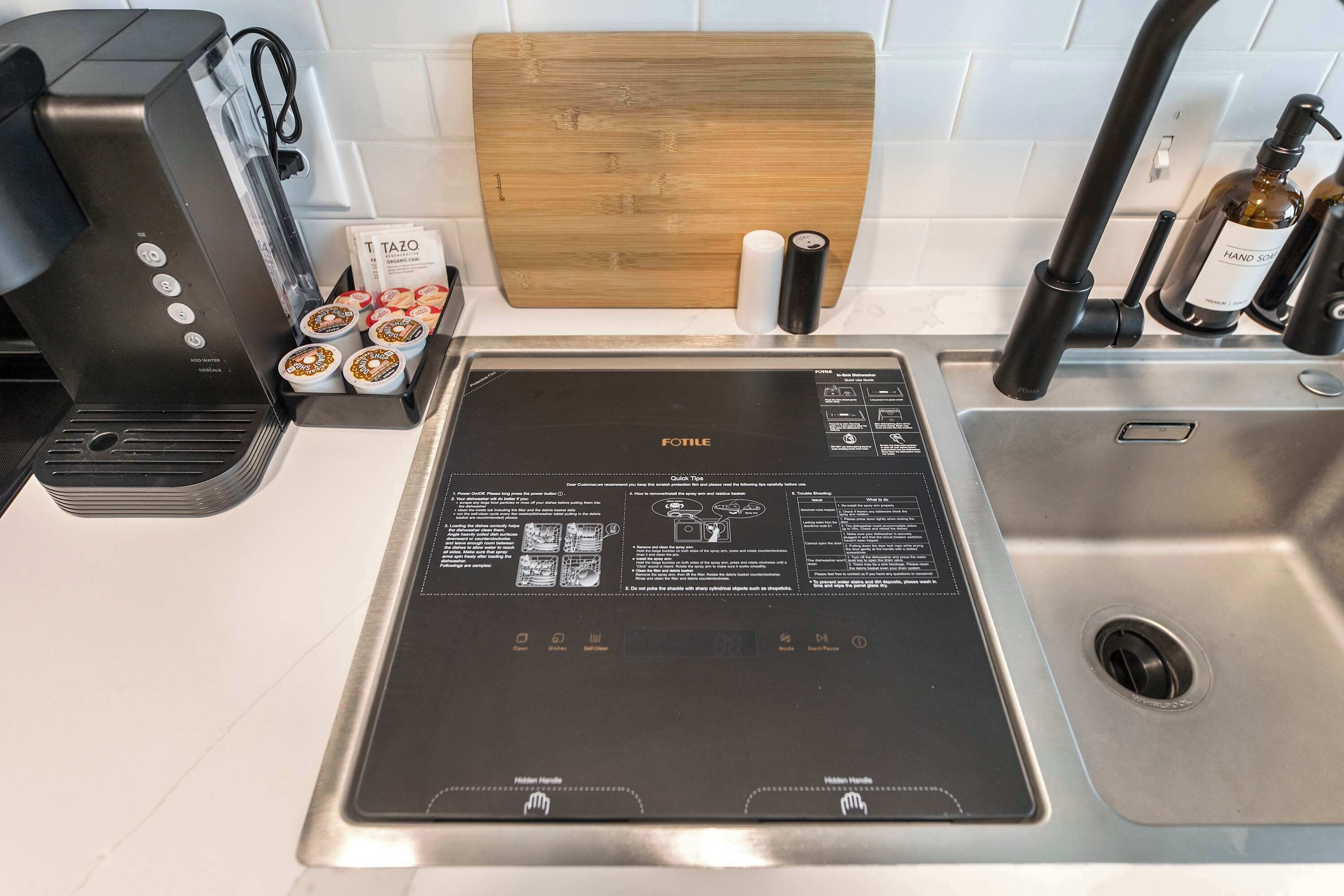 Una cocina con estufa integrada, cafetera y tabla de cortar de madera.