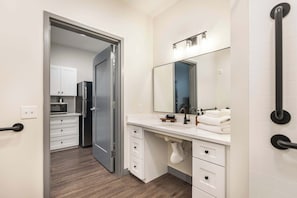 Een moderne badkamer met een grote spiegel, witte kastjes en een zichtbare wastafel.