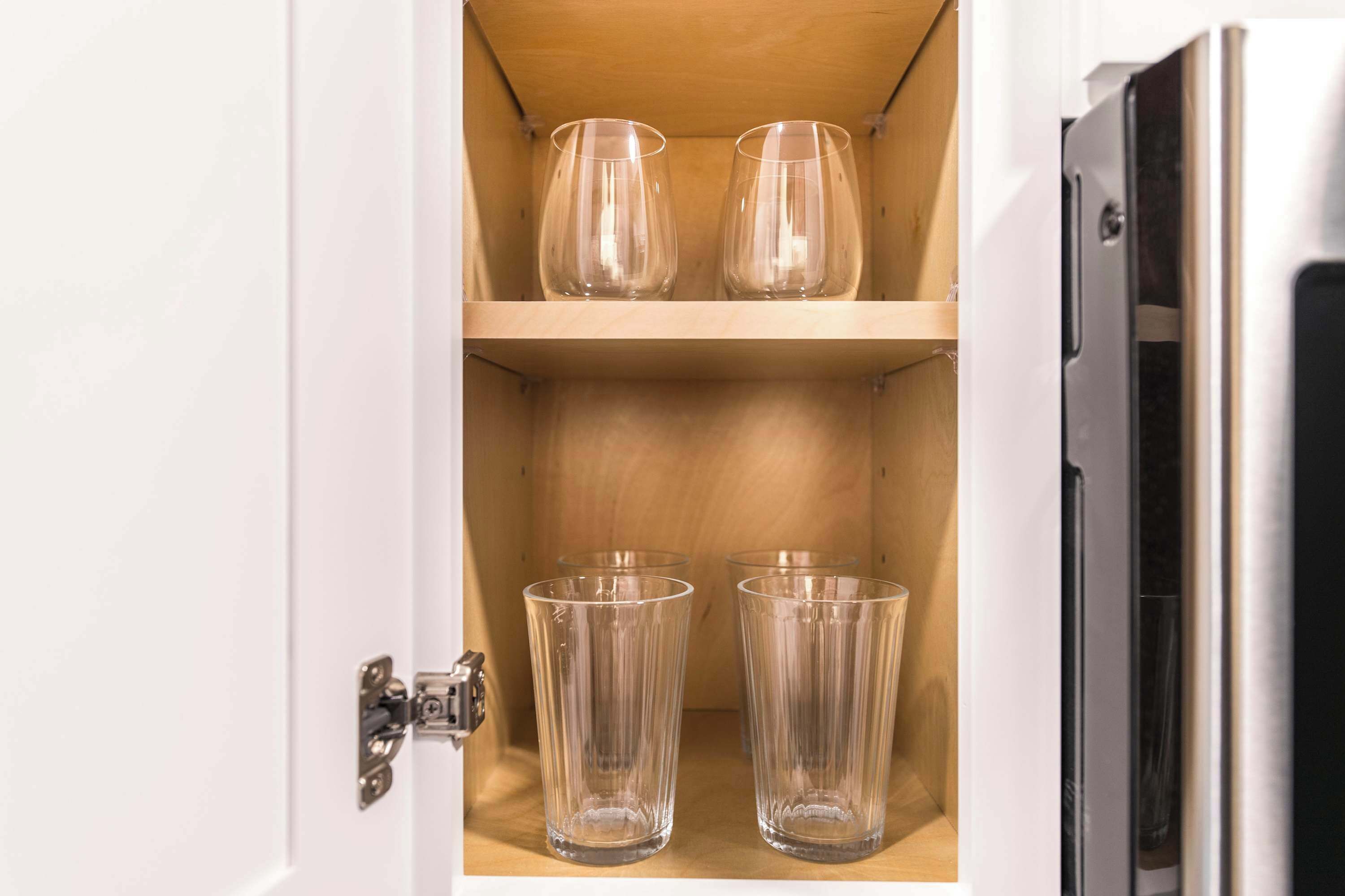 Un mueble con dos estantes, cada uno sosteniendo dos vasos transparentes.