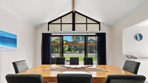 Une salle de conférence dotée d’une grande table, de chaises noires, d’un plafond en bois et offrant une vue sur la verdure environnante.