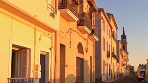 Vista de una calle con edificios que tienen balcones y un cielo despejado.