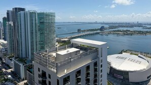 A high-rise building with a rooftop terrace, a waterfront view, and a distinctive circular building with a sign. - Sky-High Views & Pool – Steps from Miami Arena (Miami)
