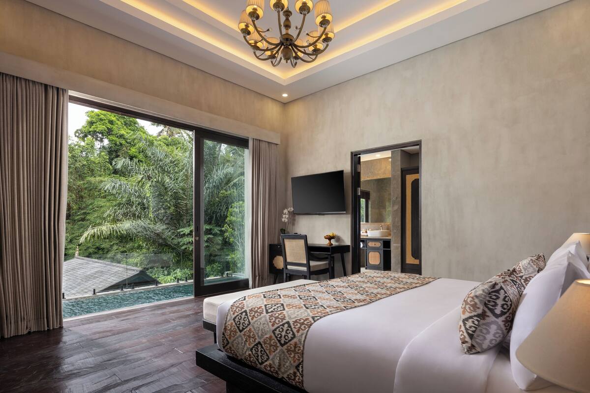 Une chambre d’hôtel avec un grand lit, un bureau, une chaise, une télévision et une salle de bain.