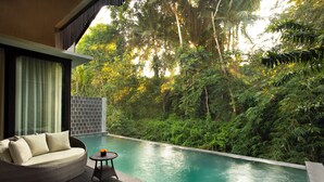 A pool area with a wicker sofa and a small table, surrounded by lush greenery. - Adiwana Unagi Riverfront (Mas)