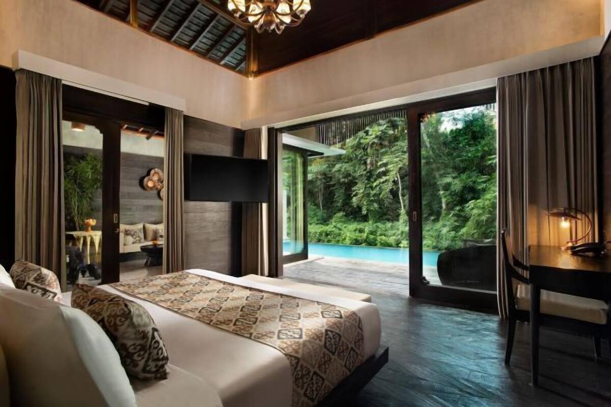 Une chambre avec un grand lit, un bureau et une vue sur une piscine.
