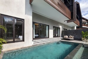 A modern house with a swimming pool, large windows, and a stone wall. - Adiwana Unagi Riverfront (Mas)