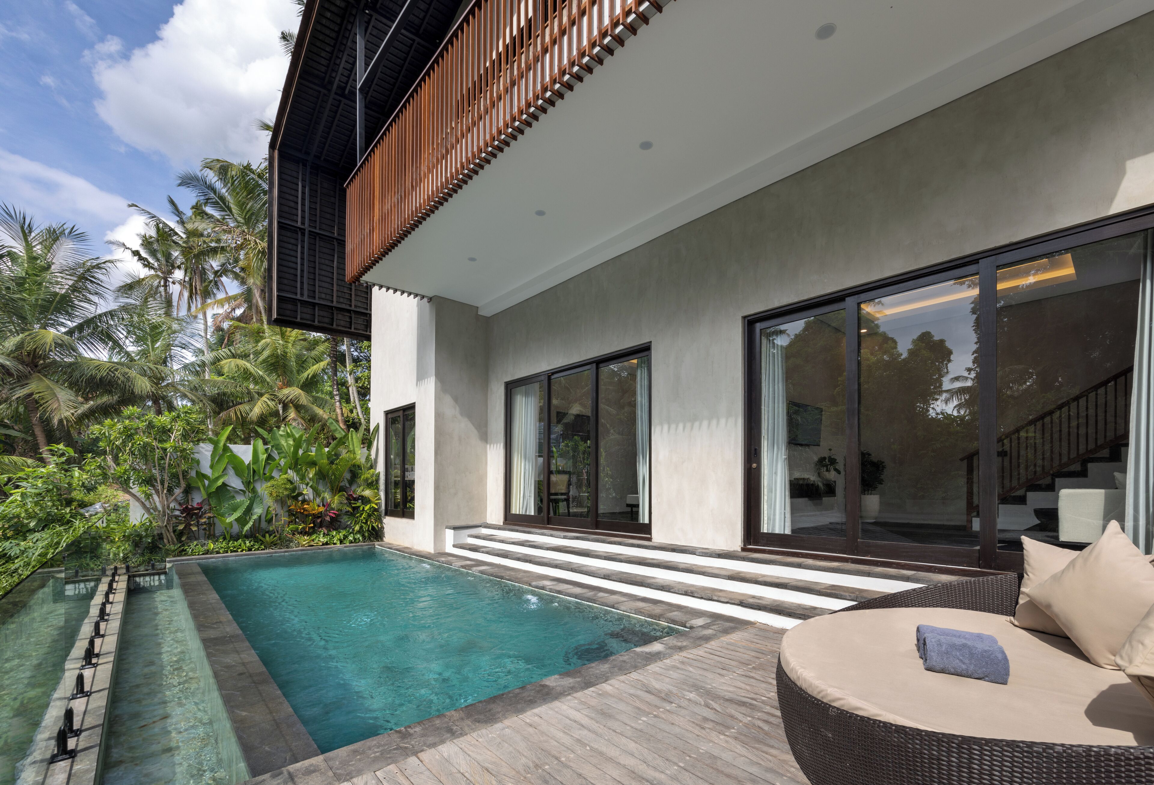 Une maison moderne dotée d’une piscine, de grandes fenêtres et d’une terrasse en bois.