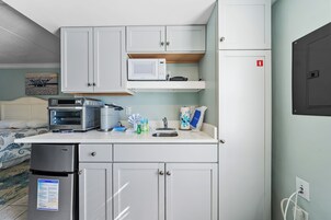 Una kitchenette compacta con microondas, tostadora y refrigerador.