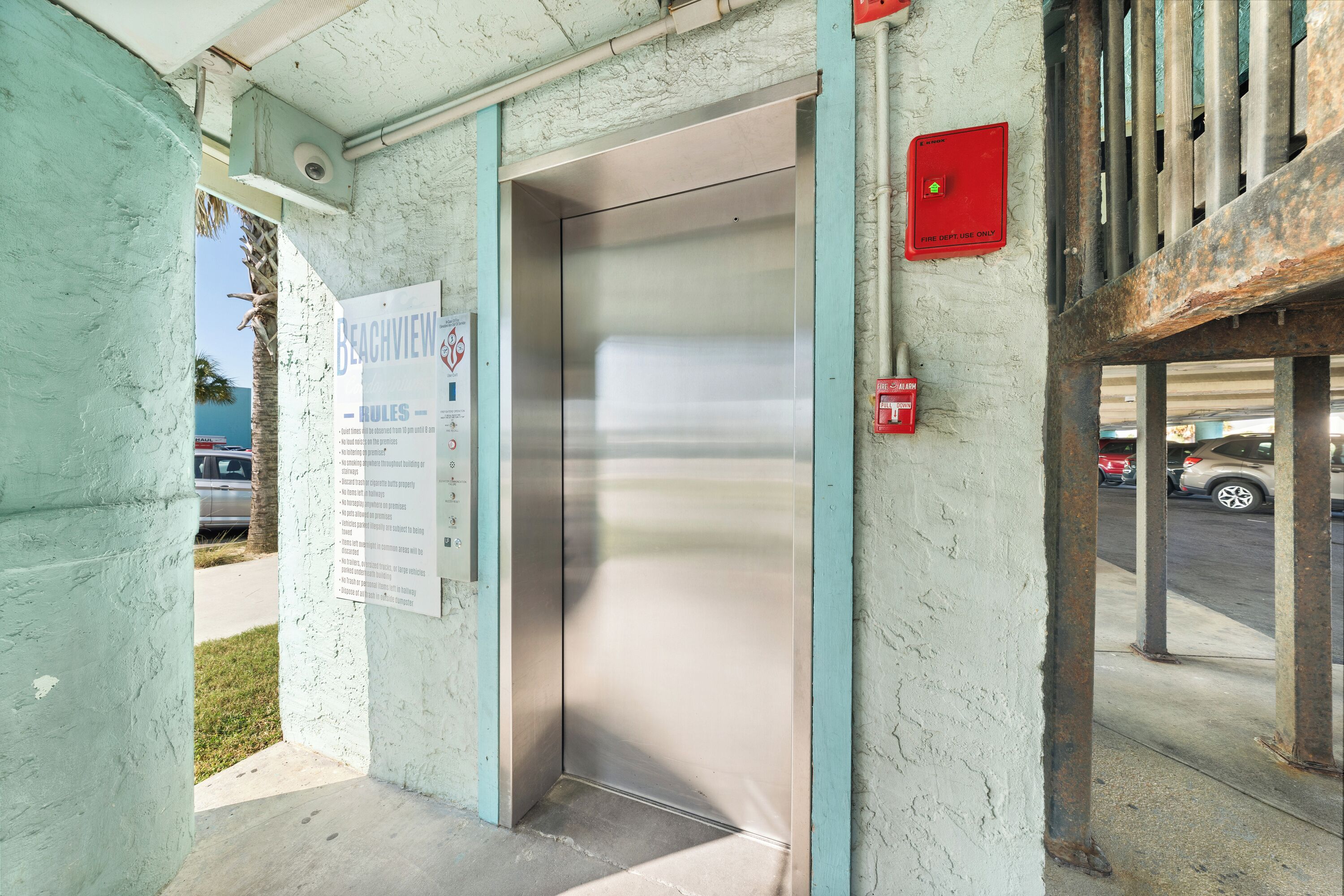 An elevator with a sign indicating it is for "BEACHVIEW" and "RULES" for the building.