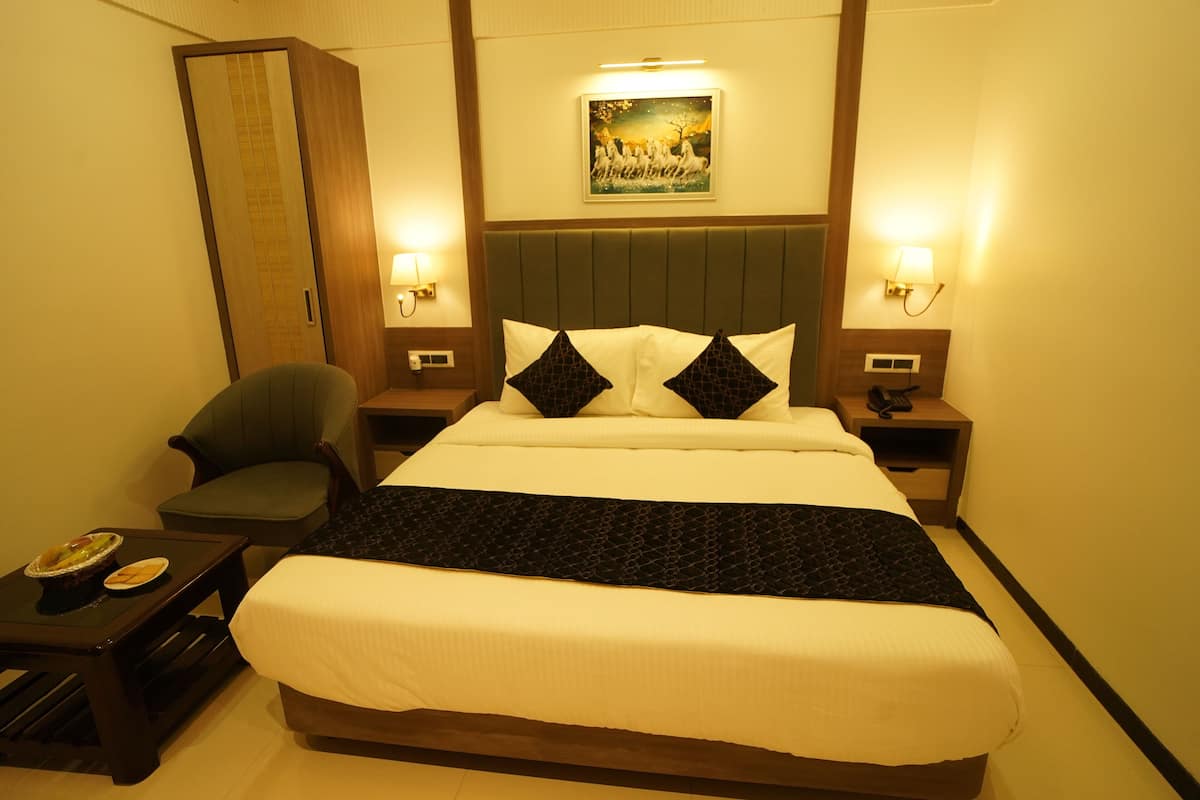 A hotel room with a bed, a chair, a nightstand, and a wall-mounted picture.