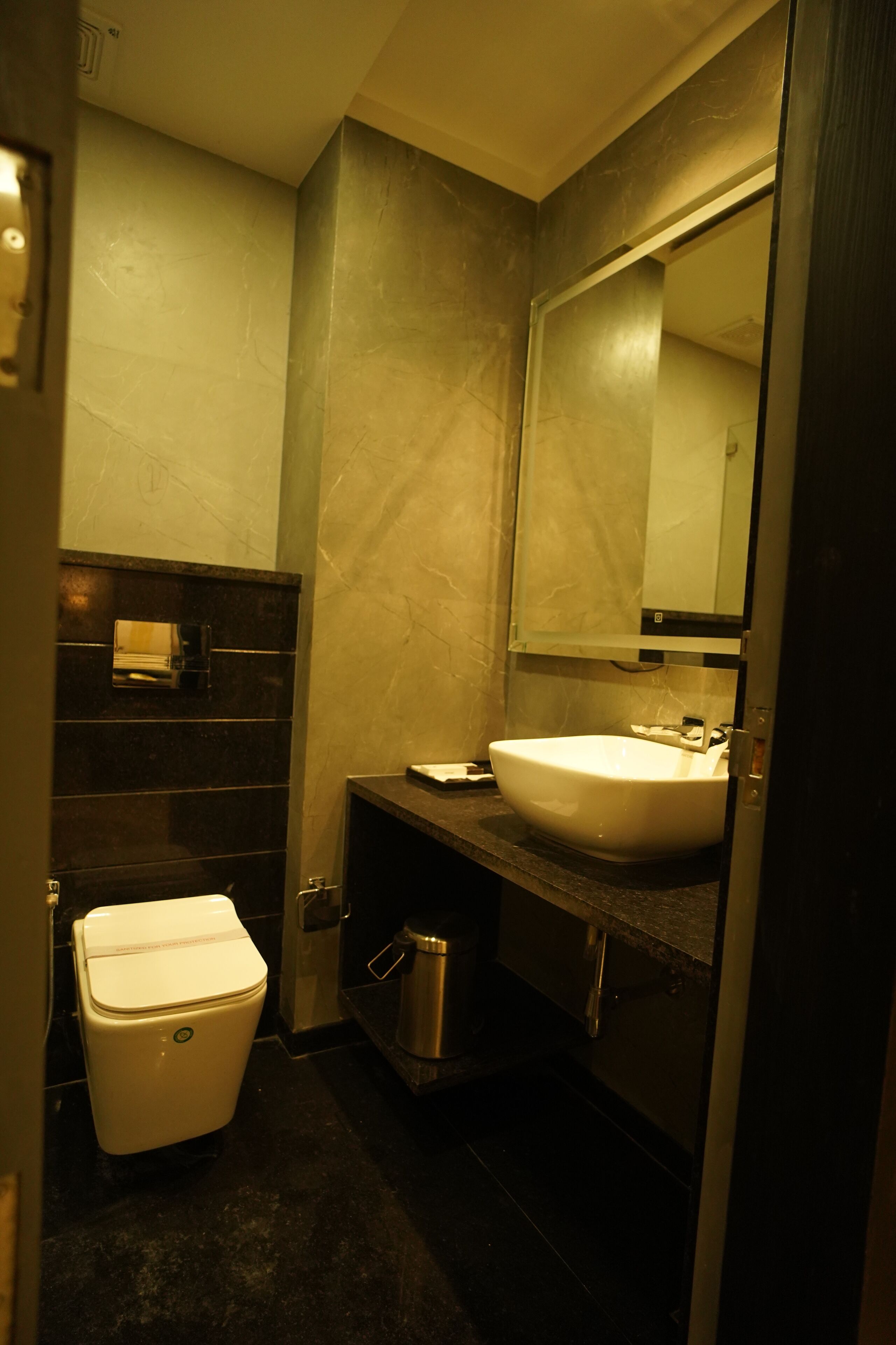 A compact bathroom with a white toilet, a sink, and a mirror.