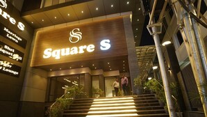 The exterior of a hotel named 'Square S' with a prominent illuminated sign, a staircase leading to the entrance, and a modern architectural design. - Hotel Square S (Varanasi)