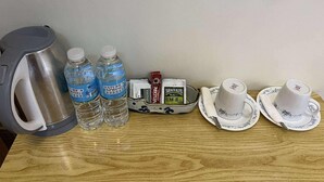 A table with a kettle, two water bottles, a coffee maker, a tea set, and a small packet of tea. - Charming Room in Delightful Compostela with Free Breakfast & Outdoor Seating  (Compostela)