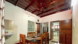 A dining area with a wooden table and chairs, a sink, and a ceiling fan.
