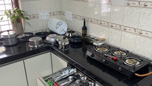 A kitchen with a stove, pots, pans, and a dish rack.