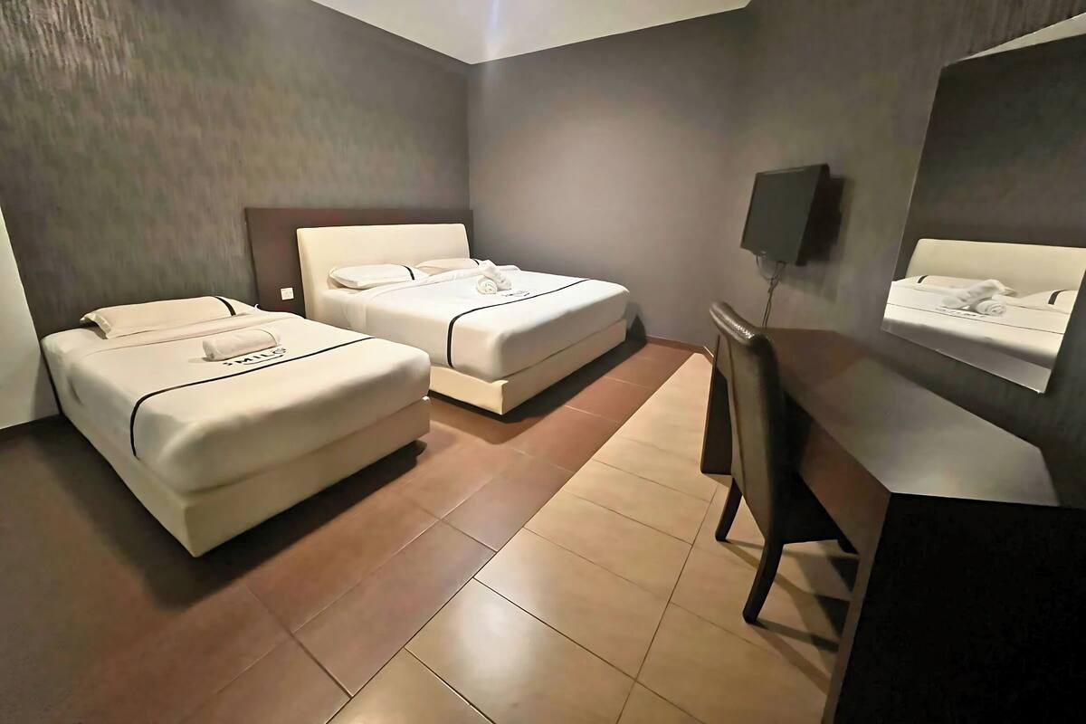Ein Hotelzimmer mit zwei Betten, einem Schreibtisch und einem Fernseher.