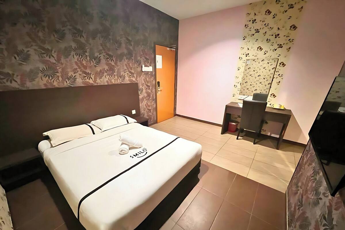 Ein Hotelzimmer mit einem großen Bett, einem Schreibtisch und einem Fernseher.