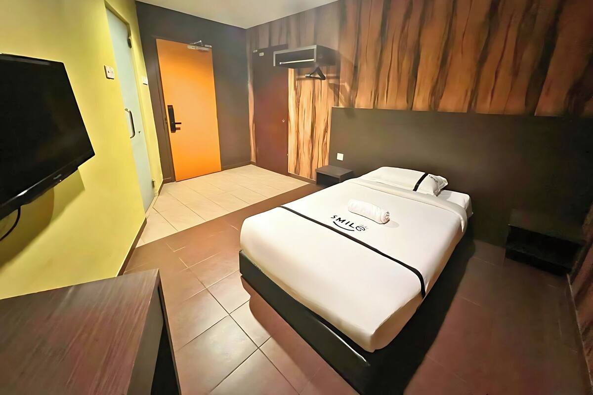 Ein Hotelzimmer mit einem Bett, einem Fernseher, einer Holzwand und einer Tür.