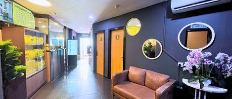 Un vestíbulo de hotel con un sofá de cuero, un mostrador de recepción y un equipo de aire acondicionado instalado en la pared.